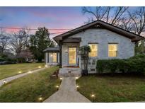 Charming white brick home with inviting walkway lighting and well-maintained lawn at dusk at 1780 John Calvin Ave, Atlanta, GA 30337