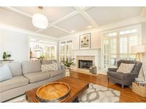 Bright living room featuring a fireplace, hardwood floors, plantation shutters, coffered ceiling, and stylish decor at 3110 Dickson Ne St, Brookhaven, GA 30319