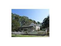 Charming home featuring a white picket fence and welcoming front porch, surrounded by mature trees under a clear blue sky at 1655 Main St, Conyers, GA 30012