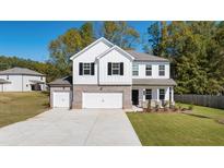 Charming two-story home featuring a brick and siding exterior with a spacious three car garage and well-maintained lawn at 2831 Centerville Rosebud Rd, Snellville, GA 30039