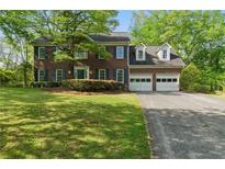 Beautiful two-story brick home with a well-manicured lawn and a two-car garage at 1550 Pine Creek Way, Woodstock, GA 30188