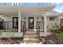 Inviting white brick home featuring a covered front porch with modern black railings and front door at 2870 Ridgemore Nw Rd, Atlanta, GA 30318