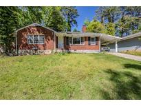 Charming brick home featuring a carport, well-maintained lawn, and mature trees at 1239 Avonwood Sw Cir, Atlanta, GA 30311
