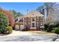 Stately brick home with mature landscaping and a two-car garage on a sunny day at 4620 Chattahoochee Se Xing, Marietta, GA 30067