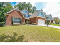 Charming brick home with a manicured lawn and two-car garage at 515 Roland Manor Dr, Dacula, GA 30019