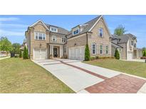 Beautiful brick home featuring a three-car garage, brick-lined driveway and manicured landscaping at 6210 Bellmoore Park Ln, Duluth, GA 30097
