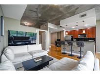 Bright living room with modern furnishings, open floor plan, and exposed concrete ceiling at 44 Peachtree Nw Pl # 629, Atlanta, GA 30309