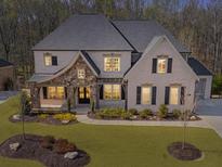 Stunning two-story home featuring stone accents, a well-manicured lawn, and beautiful landscaping at 3515 Montebello Pkwy, Cumming, GA 30028