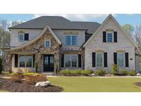 Charming two-story home with brick and stone accents, black shutters, manicured lawn and landscape in the front yard at 3515 Montebello Pkwy, Cumming, GA 30028