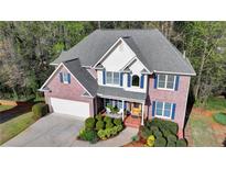Charming two-story brick home with a well-manicured lawn and classic architectural details at 5717 Harmony Point Dr, Lilburn, GA 30047