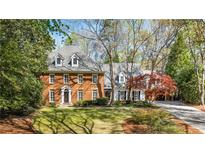 Stately brick home with dormer windows, lush landscaping, and a private driveway at 1285 Wesley Nw Pl, Atlanta, GA 30327