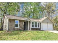 Charming single-story home with stone accents, a well-manicured lawn, and an attached two-car garage at 5477 Hedgeflower Ct, Stone Mountain, GA 30088