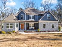 Charming two-story home featuring stone accents, blue siding, and a welcoming front porch with seating at 6710 Grayland Dr, Douglasville, GA 30135