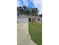 Charming single-story home with a well-maintained lawn, a combination brick and siding exterior, and an attached garage at 5760 Old Carriage Dr, Atlanta, GA 30349