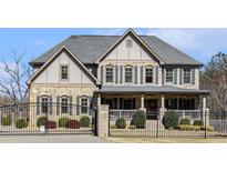 Stunning two-story home with a mix of stone and stucco, accented by black shutters and a gated entrance at 3308 Pate Rd, Snellville, GA 30078