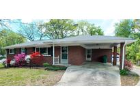Charming brick home featuring a covered parking area and a well-manicured front yard with beautiful, colorful landscaping at 4290 Chestnut Grove Ln, Austell, GA 30106