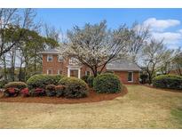 Charming two-story brick home with a well-manicured lawn and mature landscaping, including a flowering tree at 1122 Manning Farms Ct, Atlanta, GA 30338