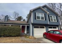 Charming two-story home features blue siding, black shutters, two car garage and a red front door at 3415 Camens Ct, Buford, GA 30519