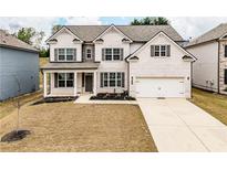 Charming two-story white brick home with a well-manicured front lawn and attached two-car garage at 3681 Deaton Trl, Buford, GA 30519
