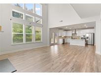 Open-concept living room featuring hardwood floors, large windows and an open view to the modern kitchen at 3681 Deaton Trl, Buford, GA 30519