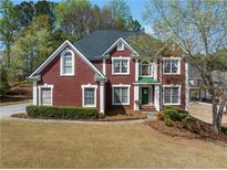 Charming red brick two-story home featuring a well-manicured lawn and mature trees at 2924 Meadow Church Rd, Suwanee, GA 30024