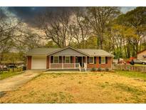 Charming single-story brick home featuring a cozy front porch and an attached one car garage at 7535 Asbury Dr, Riverdale, GA 30274