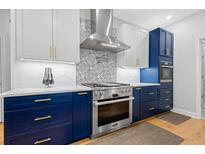 Modern kitchen with stainless steel appliances, range hood and elegant white and blue cabinets at 2105 Rotunda Ct, Conyers, GA 30094