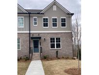 Charming townhouse featuring a brick facade, gray siding, and a well-manicured front lawn at 1250 Ainsworth Aly # 42, Sugar Hill, GA 30518