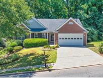 Charming brick home featuring a well-manicured lawn, mature trees, and a two-car garage at 1590 Highland Farm Dr, Suwanee, GA 30024