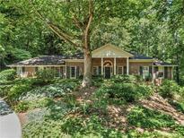 Charming brick home featuring mature trees and lush landscaping create a serene and private setting at 4590 Lake Forrest Nw Dr, Atlanta, GA 30342