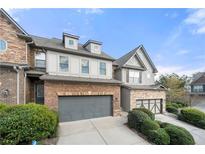 Two-story brick and stone townhome with gray garage doors and manicured landscaping at 5649 Cobblestone Creek Pl # 13, Mableton, GA 30126