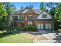 Charming brick home featuring manicured lawn, lush landscaping, and a spacious two-car garage at 3990 Old Spring House Ct, Atlanta, GA 30338