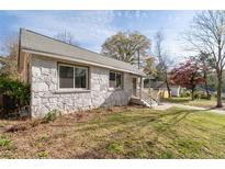 Charming stone home featuring mature trees and a well-maintained lawn on a sunny day at 1441 Ezra Church Nw Dr, Atlanta, GA 30314
