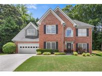 Charming two-story brick home featuring a manicured lawn and attached two-car garage at 1803 Gold Finch Way, Lawrenceville, GA 30043