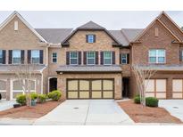 Charming brick townhouse with a two-car garage and well-maintained landscaping at 4125 Madison Bridge Dr, Suwanee, GA 30024