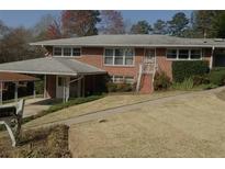 Charming brick home featuring a covered parking area, classic design elements, and a well-maintained lawn at 454 Jo Ann Se Dr, Marietta, GA 30067