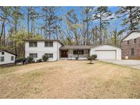 Charming two-story home with a white brick exterior and a well-manicured front yard with mature trees at 3221 Goldenchain Dr, Lithonia, GA 30038