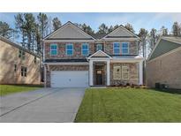 Traditional two-story brick home with a two-car garage and manicured lawn on a sunny day at 616 Leafy Branch Way, Mcdonough, GA 30253