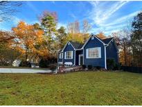 Charming blue home with white trim, mature trees, and well-manicured lawn, offering great curb appeal at 3337 Camens Way, Buford, GA 30519
