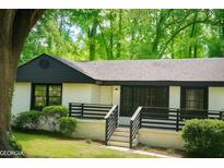 Charming single-story home featuring white stucco and black trim in a lush, green setting at 1956 Shirley Sw St, Atlanta, GA 30311