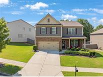 Charming two-story home featuring a brick and gray facade, well-manicured lawn, and an attached two-car garage at 1252 Thomas Daniel Way, Lawrenceville, GA 30045