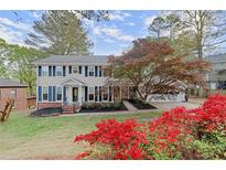 Charming two-story home with manicured lawn, colorful landscaping, and blue shutters at 1196 Oak Sw Rd, Lilburn, GA 30047