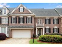Charming brick townhome featuring an attached garage, black shutters, and manicured landscaping in a desirable community at 611 Vinings Estates Se Dr, Smyrna, GA 30126