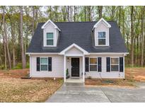 Charming two-story home with black shutters and dormer windows, set against a backdrop of lush trees at 214 Walton St, Loganville, GA 30052