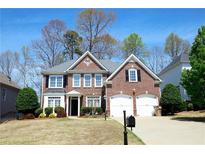 Charming two-story brick home with a well-manicured lawn and a two-car garage at 5712 Kendrick Ln, Cumming, GA 30041