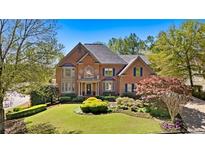 Beautiful two-story brick home with a manicured front lawn and mature trees in a desirable neighborhood at 9985 High Falls Pointe, Johns Creek, GA 30022