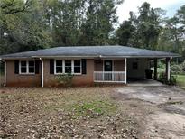 Charming brick ranch-style home with a covered carport and mature trees at 2369 Christian Cir, Covington, GA 30016