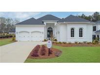 Beautiful white brick home with a manicured lawn, arched windows, a two-car garage and a dark, arched front door at 103 Candler Loop, Acworth, GA 30101