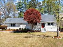 Charming single-story home with a well-manicured lawn and inviting front porch, highlighted by a vibrant red tree at 385 Jayne Ellen Way, Alpharetta, GA 30009
