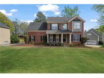 Beautiful brick two-story home with a manicured lawn, classic shutters, and charming front porch at 45 Cherrystone Walk, Suwanee, GA 30024